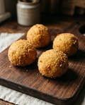 Homemade Italian arancini with golden breadcrumb coating on a wooden board