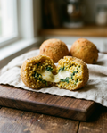 Arancino split open showing rice, spinach and melted mozzarella filling