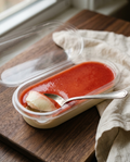 Spoon lifting a scoop of panna cotta, showing the silky set texture under the strawberry sauce