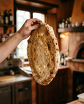 Italian pizza base held up to the light showing its airy naturally leavened dough