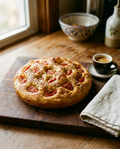 Focaccia Barese on a board beside an espresso cup for size reference