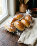 Four milk bread rolls sealed in a clear bag, as they arrive